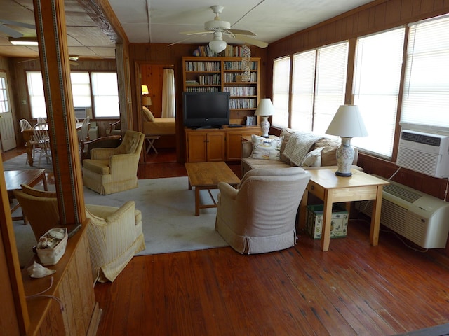 living area with light wood-style floors, ceiling fan, cooling unit, and wood walls