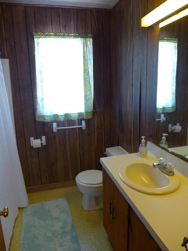 bathroom featuring wooden walls, toilet, and vanity