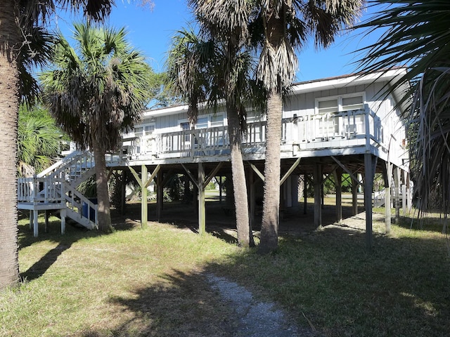 back of property with stairs, a lawn, a deck, and a carport