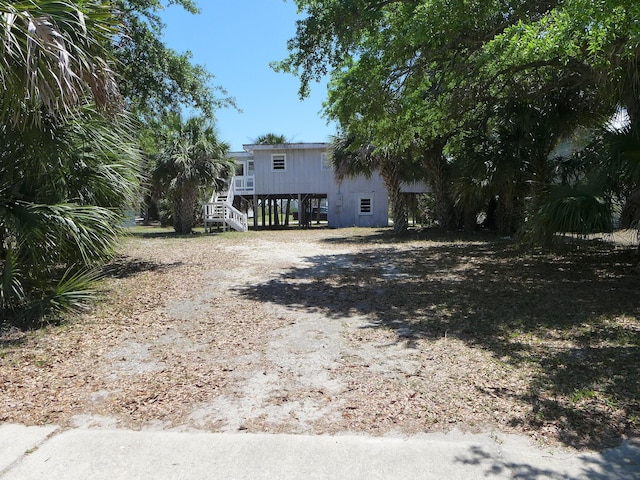 exterior space featuring a carport, stairs, and dirt driveway
