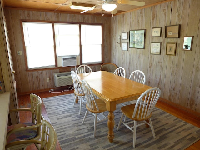 dining room with plenty of natural light, ceiling fan, cooling unit, and wooden walls