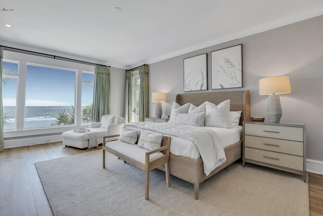 bedroom with a water view and light hardwood / wood-style floors