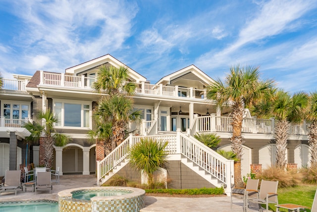 view of front of house featuring a porch, a patio, a balcony, and a pool with hot tub