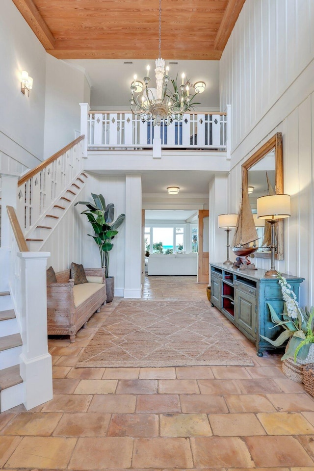 entryway featuring a towering ceiling, wooden walls, wooden ceiling, and a notable chandelier