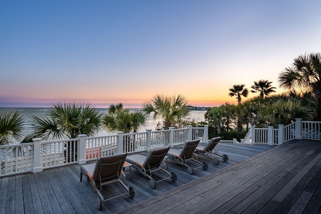 deck at dusk featuring a water view