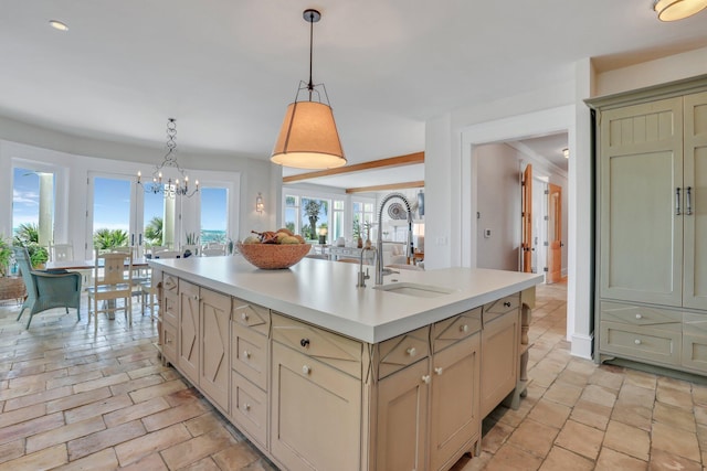 kitchen with sink, a notable chandelier, cream cabinets, an island with sink, and decorative light fixtures