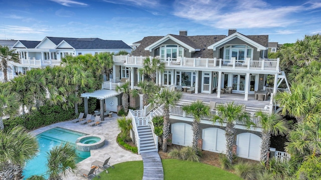 rear view of house featuring a pool with hot tub, a balcony, and a patio