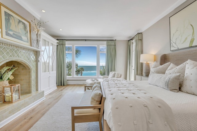 bedroom with light hardwood / wood-style floors and a water view