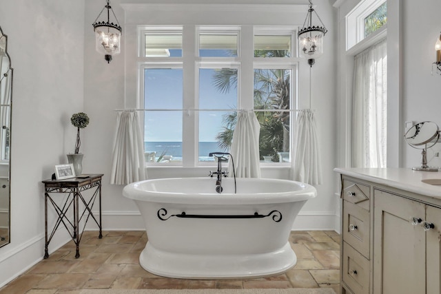 bathroom featuring a washtub, a healthy amount of sunlight, a water view, and vanity