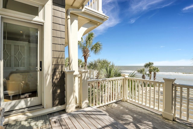 wooden deck featuring a water view and a beach view