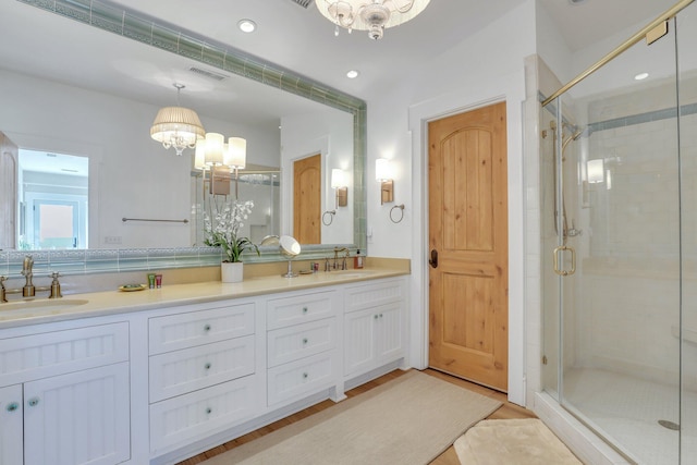 bathroom featuring hardwood / wood-style flooring, vanity, a shower with shower door, and an inviting chandelier