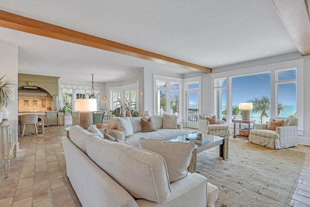 living room with a chandelier, beam ceiling, and plenty of natural light