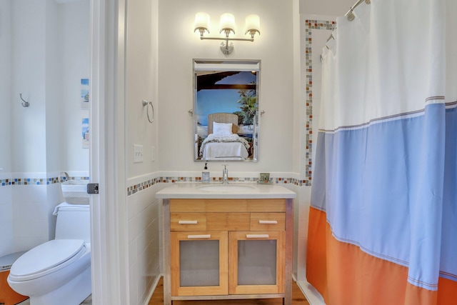 bathroom with walk in shower, vanity, toilet, and tile walls