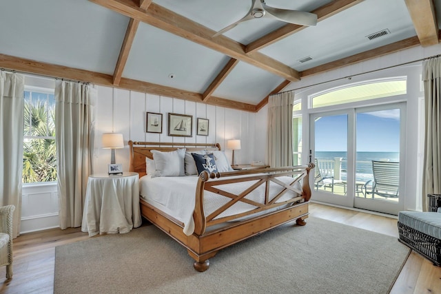 bedroom with access to outside, a water view, light hardwood / wood-style flooring, and multiple windows