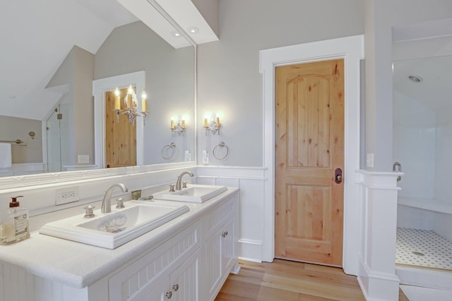 bathroom featuring a shower, vanity, wood-type flooring, and vaulted ceiling