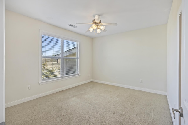 empty room with a ceiling fan, light colored carpet, visible vents, and baseboards