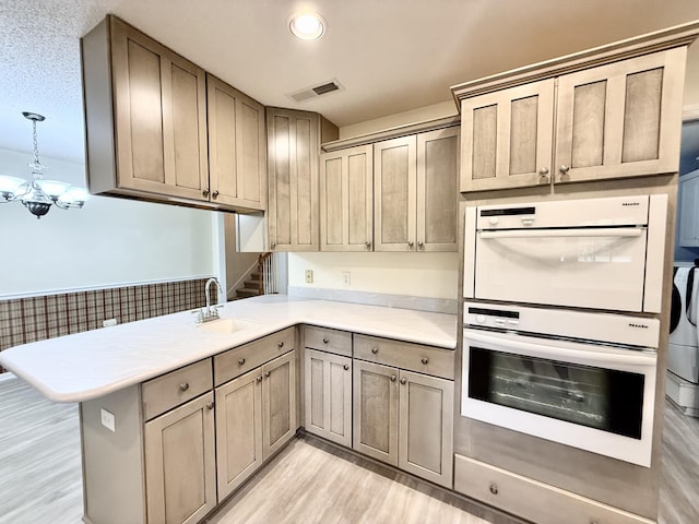 209 Myrtlewood Dr, Santee, SC 29142 - kitchen with white double oven, a peninsula, light wood-style floors, a chandelier, and light countertops