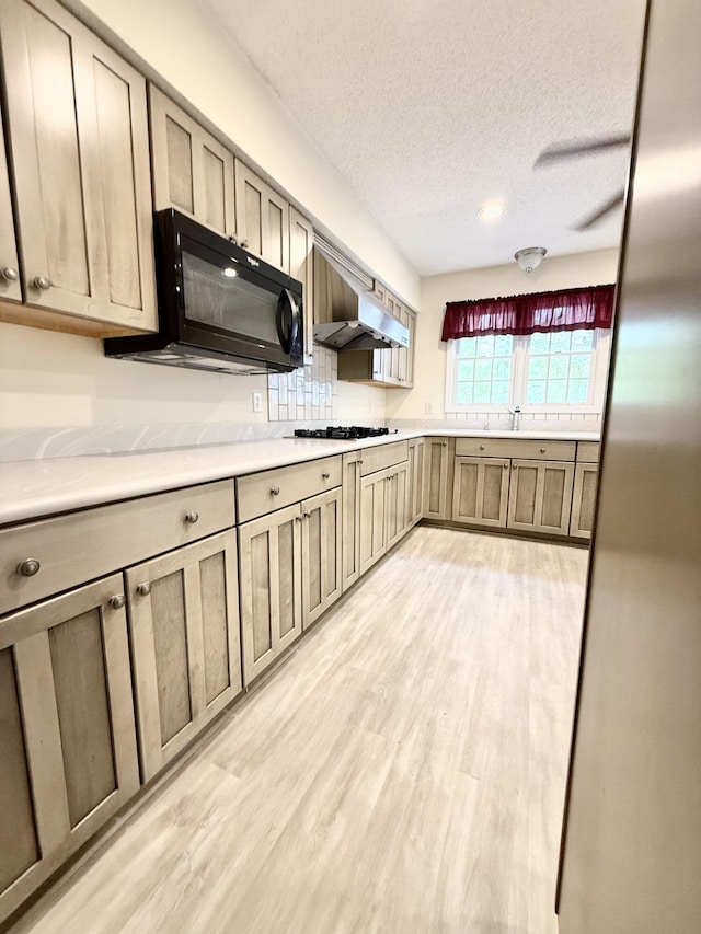 209 Myrtlewood Dr, Santee, SC 29142 - kitchen featuring black microwave, light wood-style flooring, gas cooktop, a textured ceiling, and under cabinet range hood