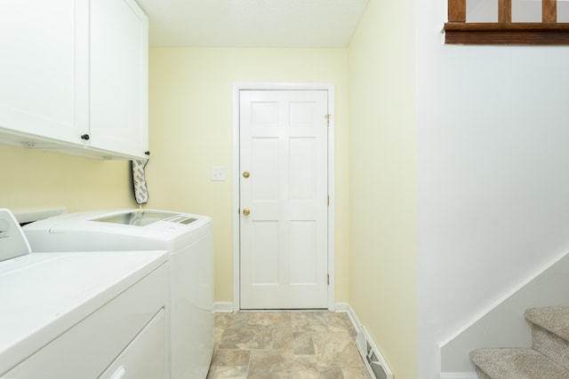 clothes washing area with washer and dryer, light tile patterned flooring, and cabinets