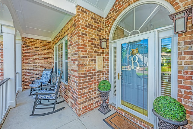 entrance to property with covered porch and brick siding