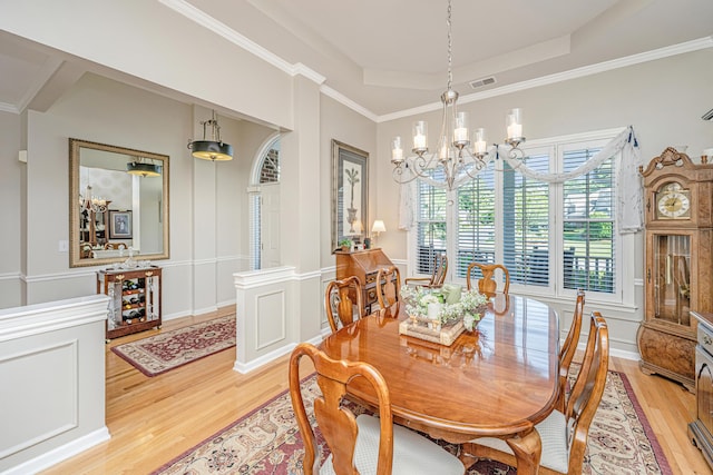 dining area featuring a chandelier, light wood-style flooring, a tray ceiling, visible vents, and ornamental molding
