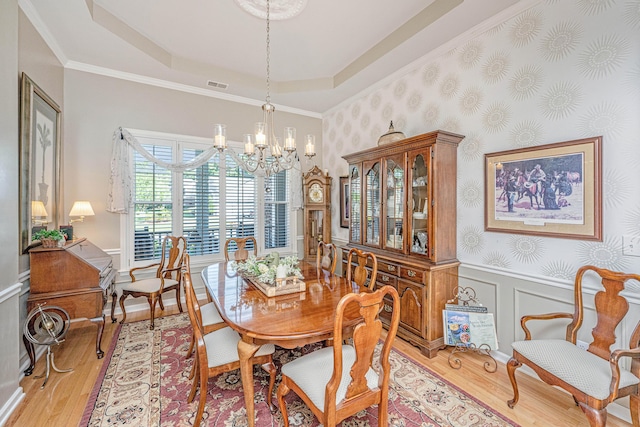 dining room with an inviting chandelier, visible vents, wainscoting, light wood-type flooring, and a tray ceiling