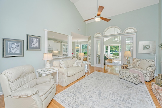 living room featuring visible vents, ceiling fan, high vaulted ceiling, ornate columns, and light wood finished floors