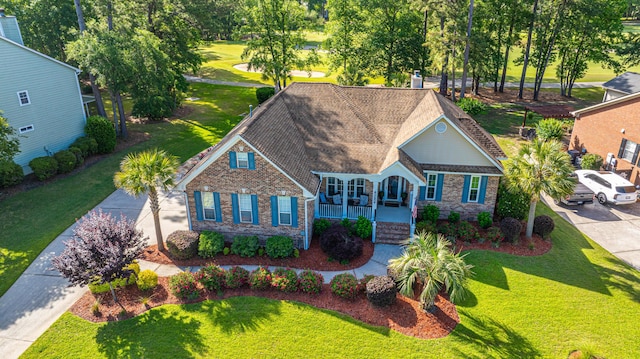 view of front of home featuring brick siding, a front lawn, covered porch, and concrete driveway