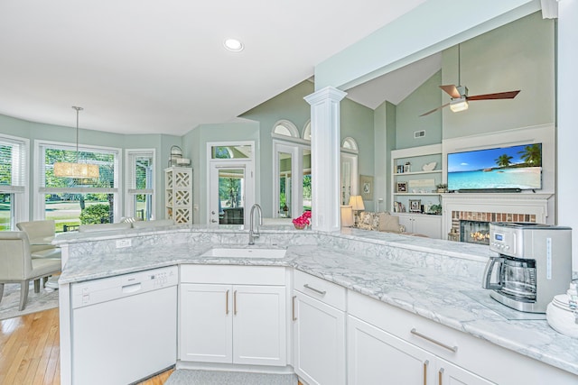 kitchen with a ceiling fan, light stone countertops, open floor plan, a sink, and dishwasher