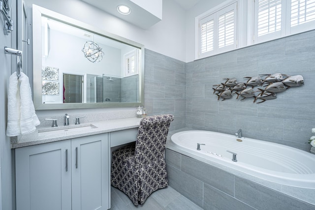 bathroom featuring an inviting chandelier, vanity, a tile shower, and a bath