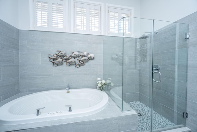 full bathroom with a shower stall, a healthy amount of sunlight, and a garden tub