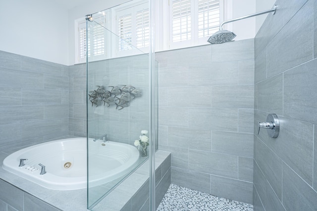 bathroom featuring a tub with jets and a tile shower