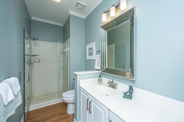 bathroom featuring ornamental molding, a shower stall, toilet, and wood finished floors