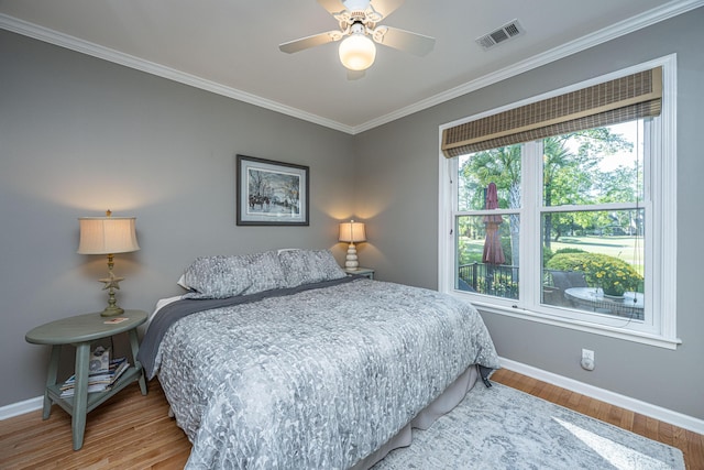 bedroom with a ceiling fan, visible vents, crown molding, wood finished floors, and baseboards
