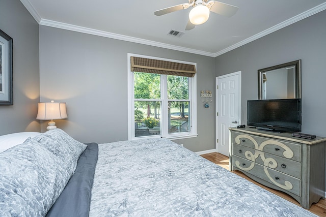 bedroom featuring crown molding, baseboards, wood finished floors, and visible vents