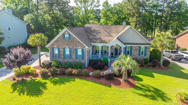 view of front of house featuring a porch, a front lawn, and brick siding
