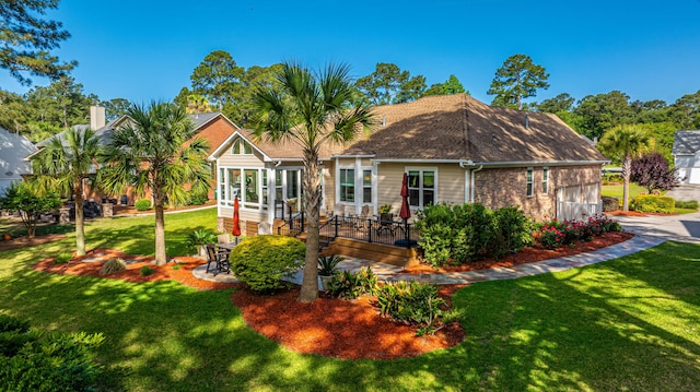 back of property with a lawn, a deck, a garage, brick siding, and concrete driveway