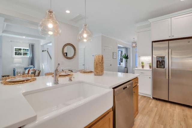 kitchen featuring white cabinetry, sink, stainless steel appliances, decorative light fixtures, and light wood-type flooring