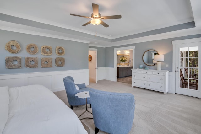 bedroom featuring ensuite bath, access to outside, a tray ceiling, ceiling fan, and light colored carpet