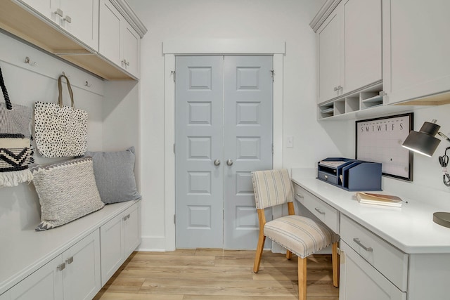 mudroom with light hardwood / wood-style floors and built in desk