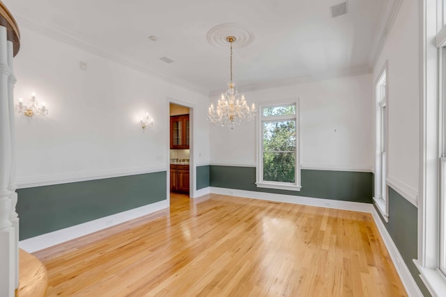 unfurnished room featuring a notable chandelier, light wood-type flooring, and ornamental molding