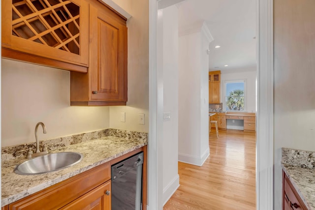 kitchen with light stone counters, black dishwasher, crown molding, light hardwood / wood-style flooring, and sink