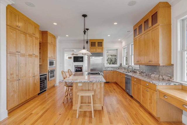 kitchen with light wood-type flooring, wine cooler, built in appliances, a kitchen island, and decorative light fixtures