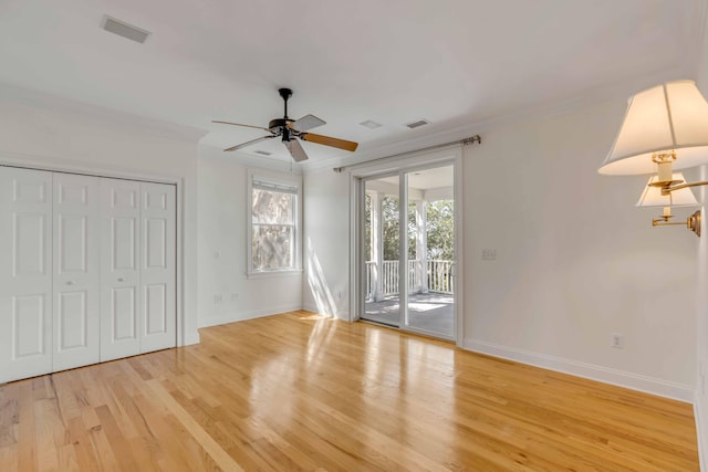 unfurnished bedroom with a closet, light hardwood / wood-style floors, access to outside, ornamental molding, and ceiling fan