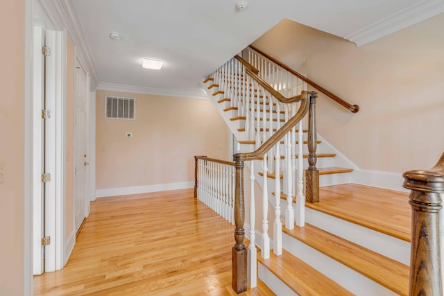 stairs with wood-type flooring and crown molding