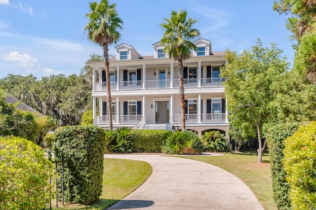 view of front facade with a balcony, a front lawn, and covered porch