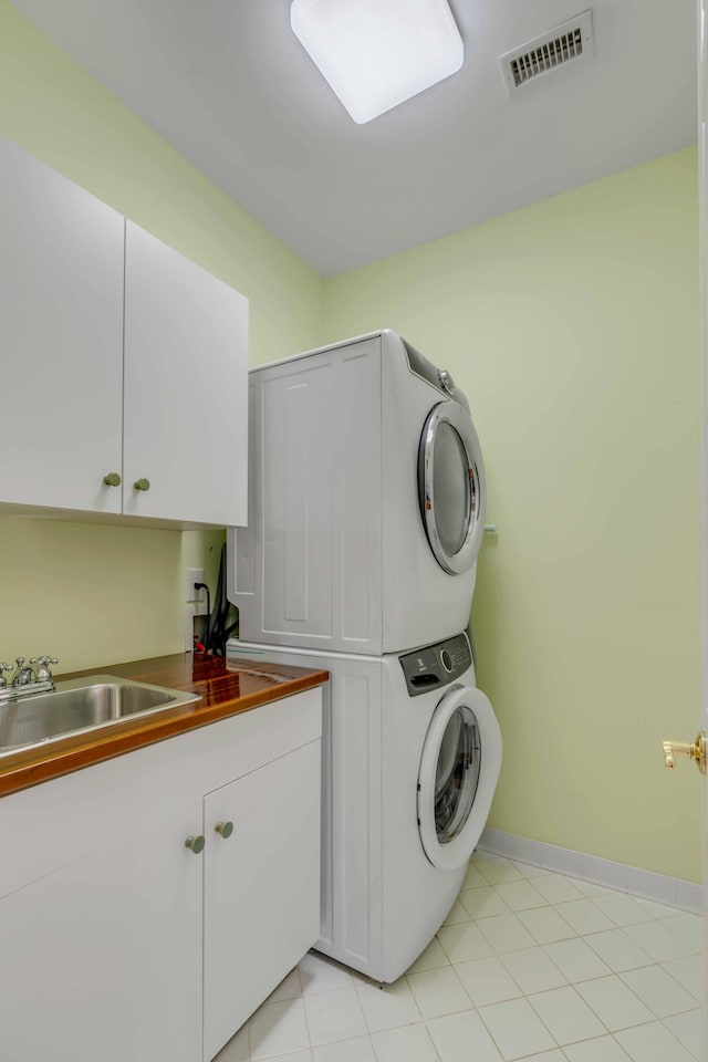 laundry room with cabinets, stacked washer / dryer, and sink