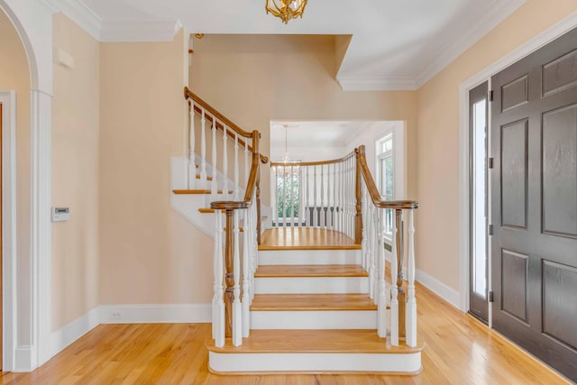 foyer entrance with hardwood / wood-style flooring, crown molding, and a notable chandelier