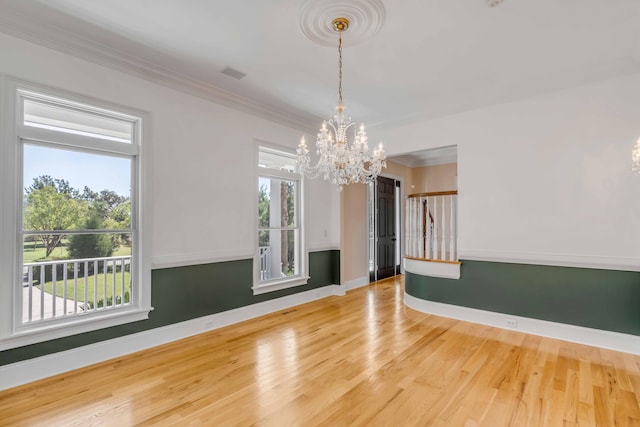 spare room featuring an inviting chandelier, ornamental molding, and hardwood / wood-style floors