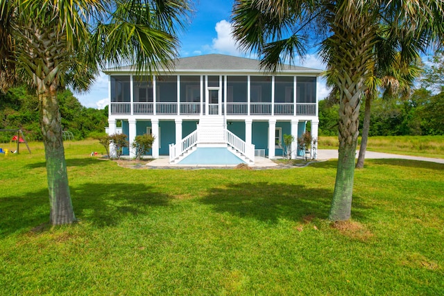 rear view of property featuring a patio, a yard, and a sunroom